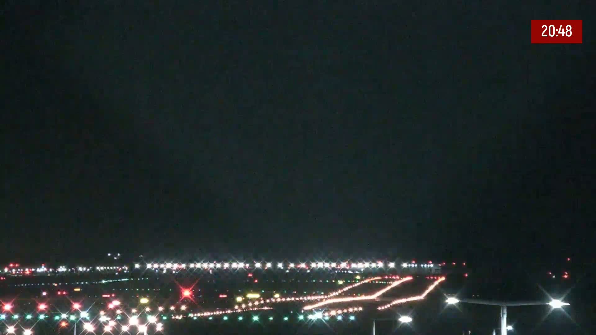 A nighttime long shot of brightly lit airport runways and taxiways under a dark sky.