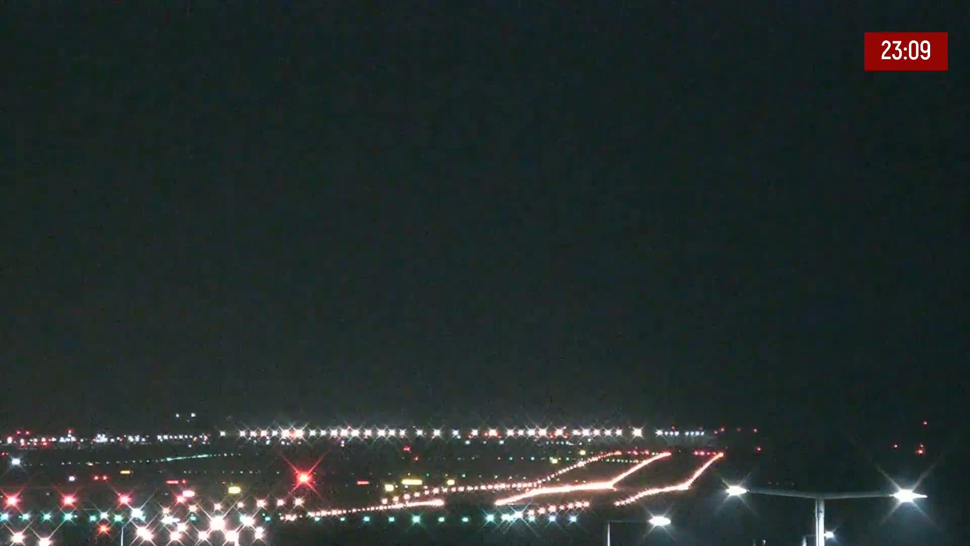 A nighttime view of a brightly lit airport runway under a dark, clear sky.