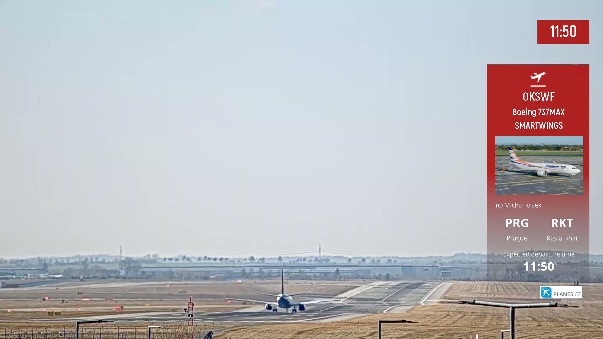 A passenger airplane is taxiing on a runway toward takeoff under hazy conditions.