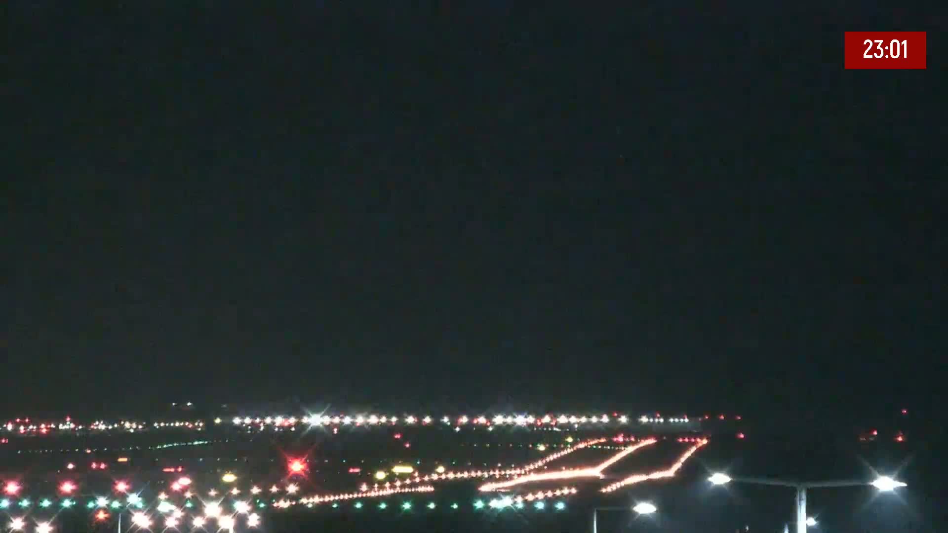 A nighttime view of an airport runway with numerous lights illuminating the taxiways and runways under a clear, dark sky.