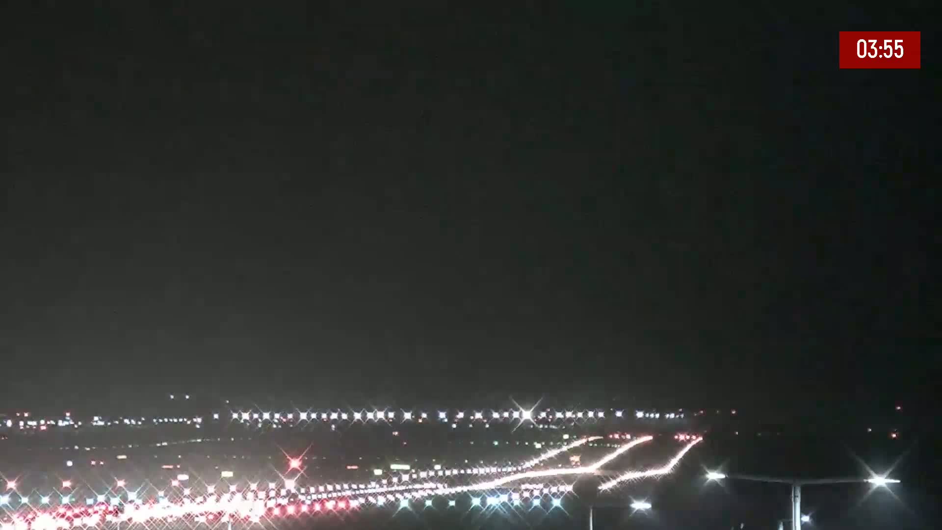 Under a dark night sky, a long stretch of highway is illuminated by the headlights of numerous vehicles traveling in both directions.
