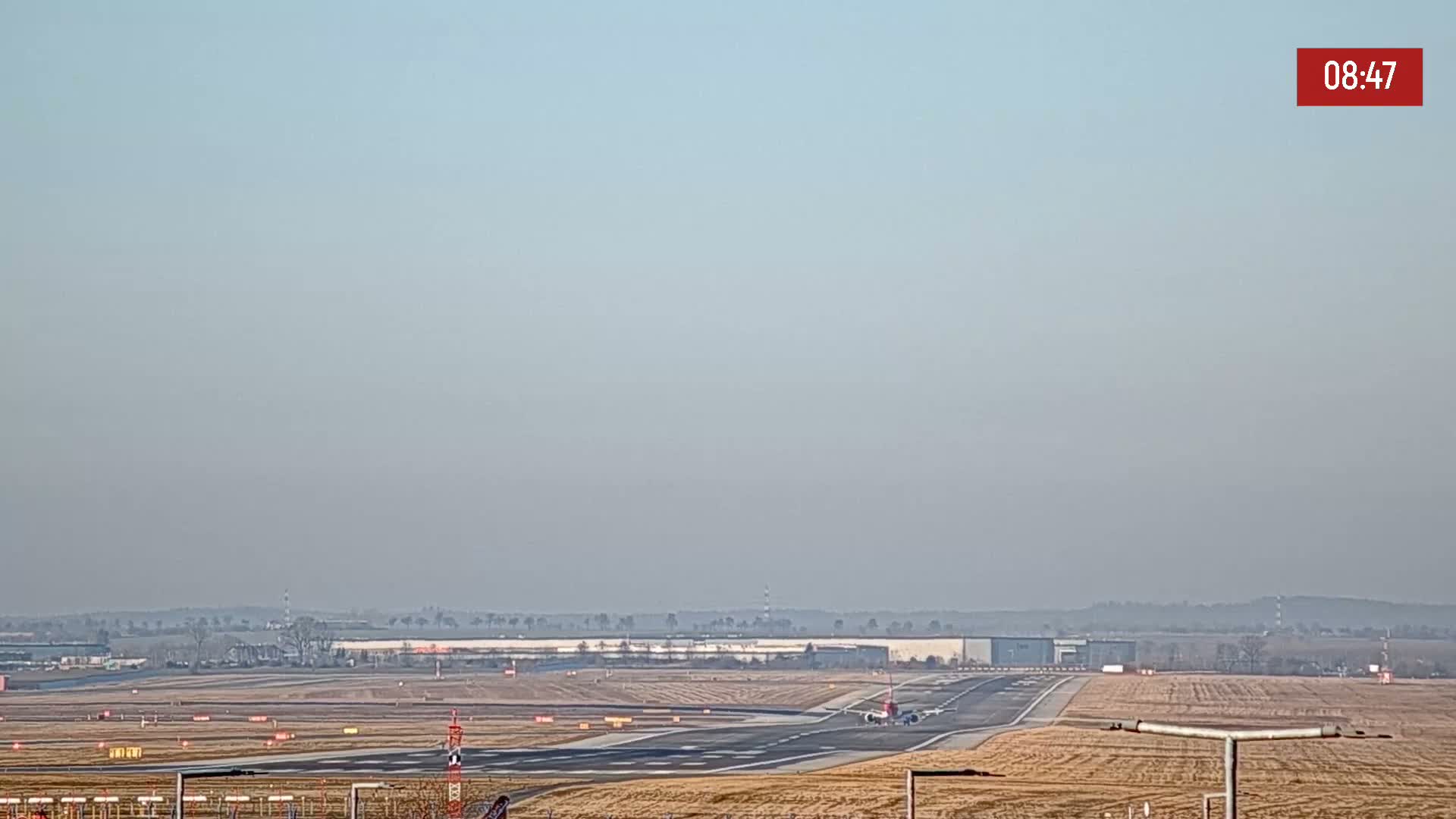 An airplane taxis on a runway at an airport on a hazy day.