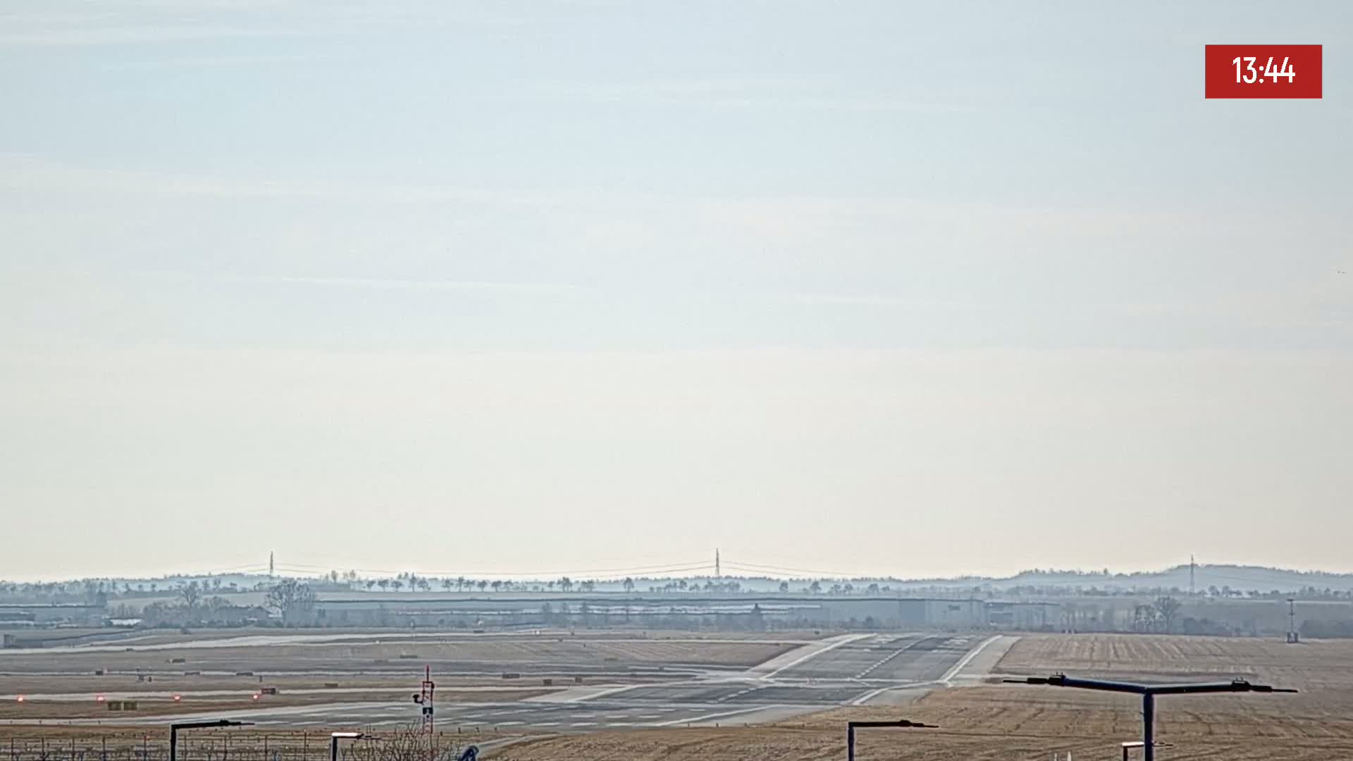 A hazy, distant view of an airport runway and surrounding flat land under a pale sky.