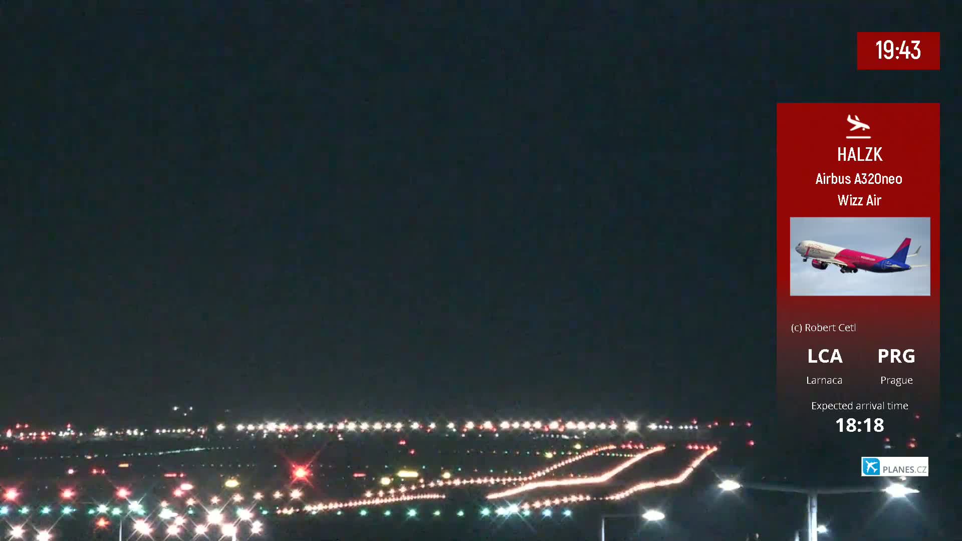 A nighttime view of an airport runway with lights illuminated, under a dark sky.