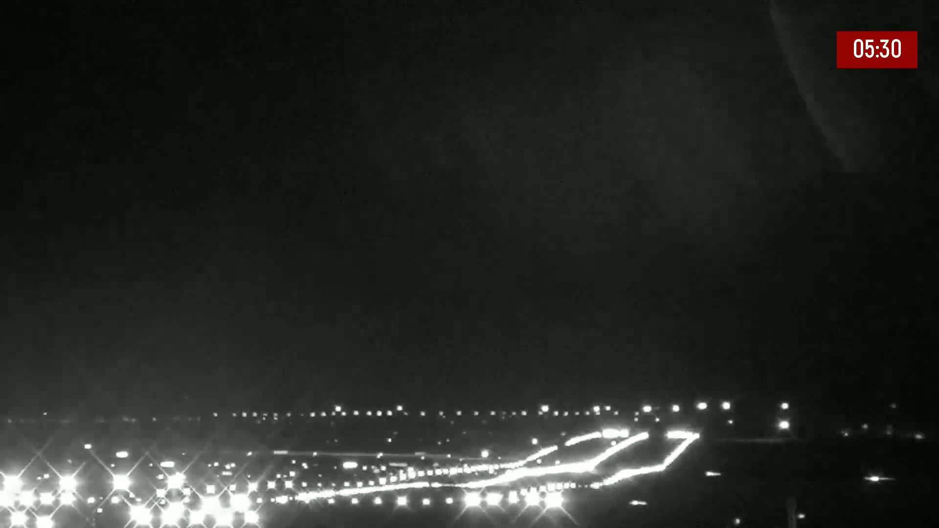 A nighttime long shot shows a highway with numerous vehicle headlights visible under a dark, possibly cloudy sky.