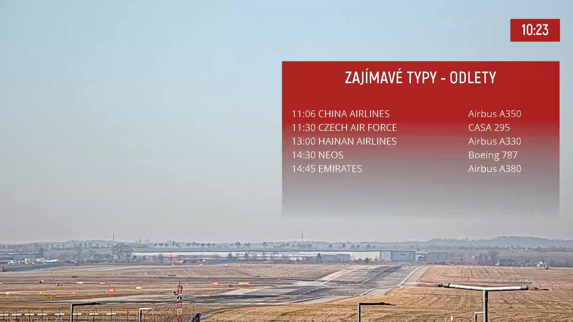 A long shot of an airport runway on a hazy day shows the tarmac and surrounding landscape.