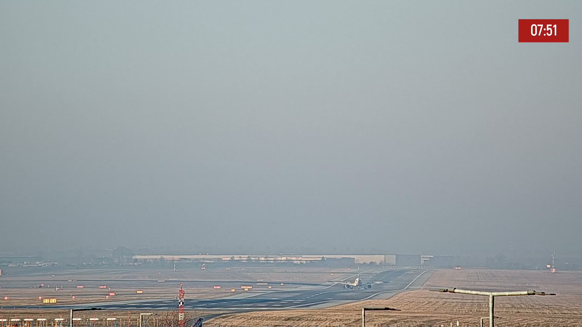 A passenger plane taxis on a runway at an airport under hazy conditions.