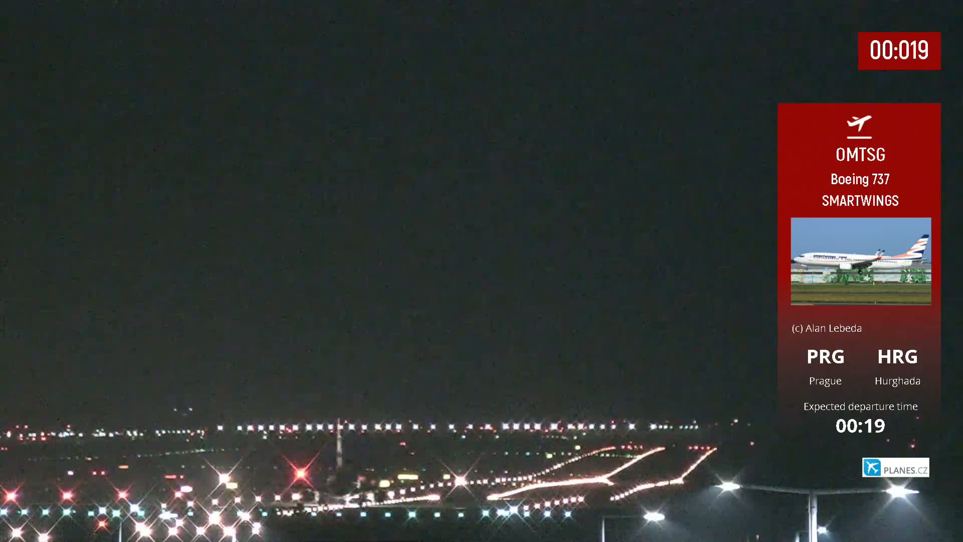 A nighttime view of an airport runway with lights illuminating the tarmac and surrounding area under a dark sky.