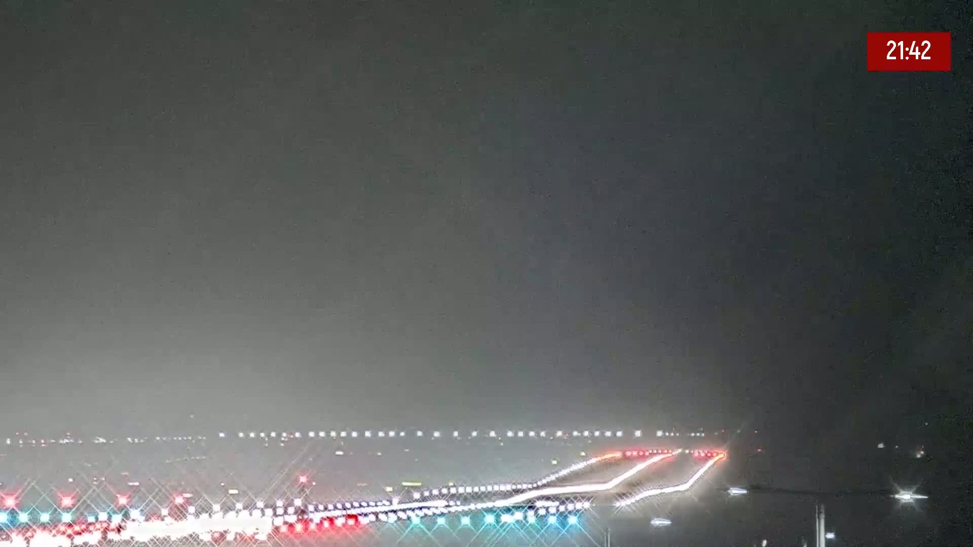 A hazy night scene shows a highway with cars driving under dim lighting.