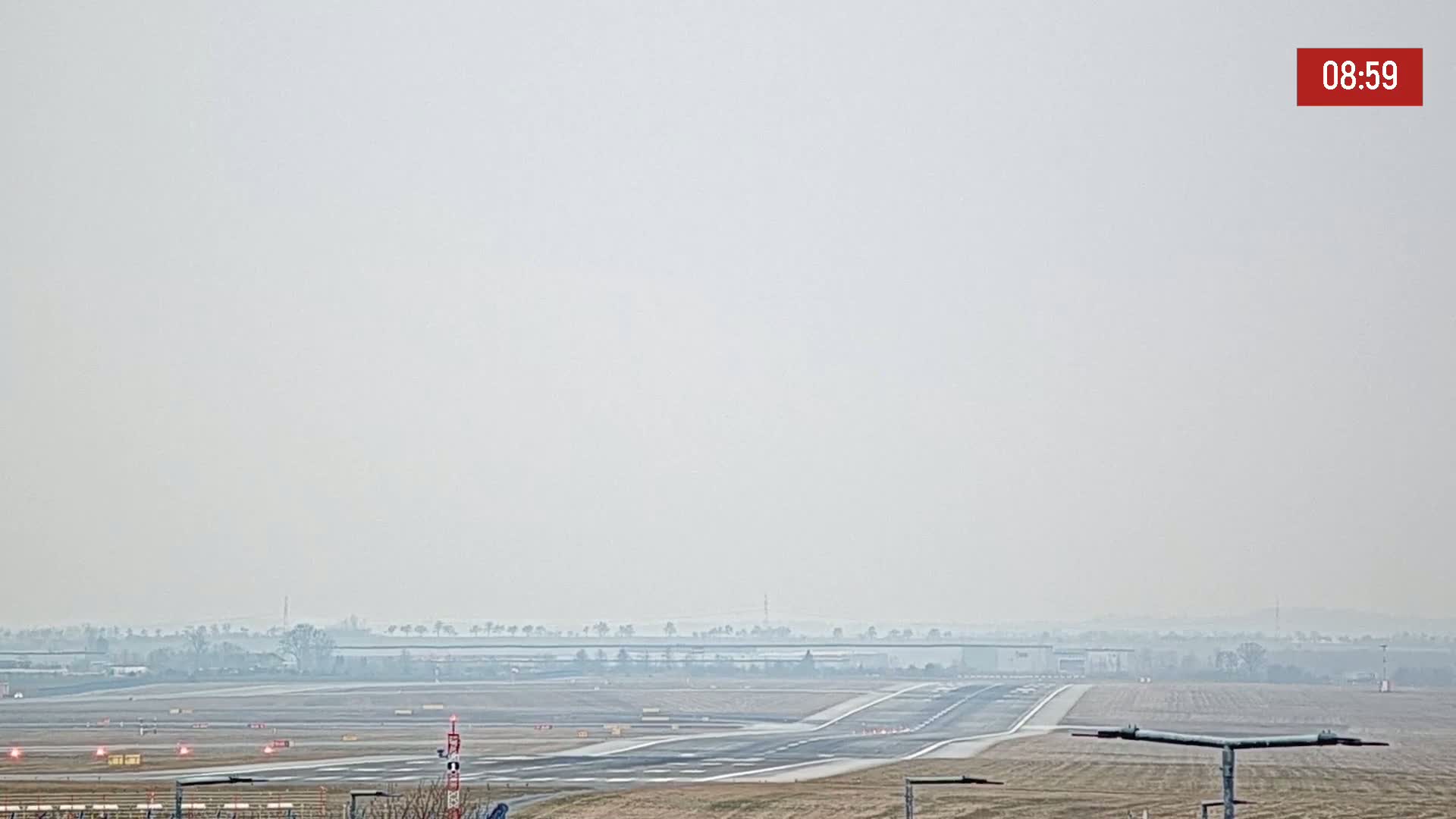 A hazy view of an airport runway and surrounding flat land.