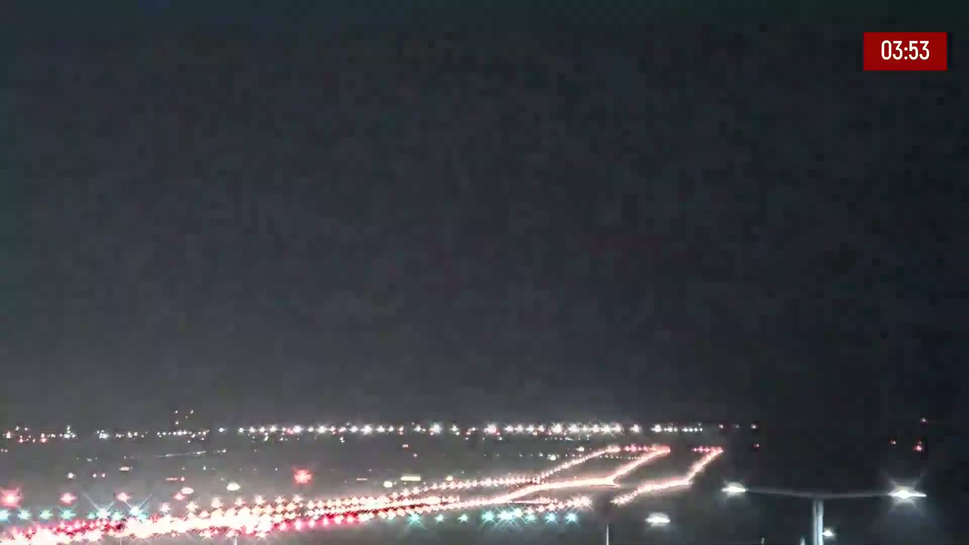 A nighttime long shot of a highway with heavy traffic under a dark sky.