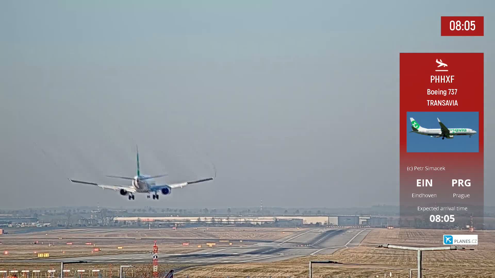 A Transavia Boeing 737 is landing on a runway on a hazy day.
