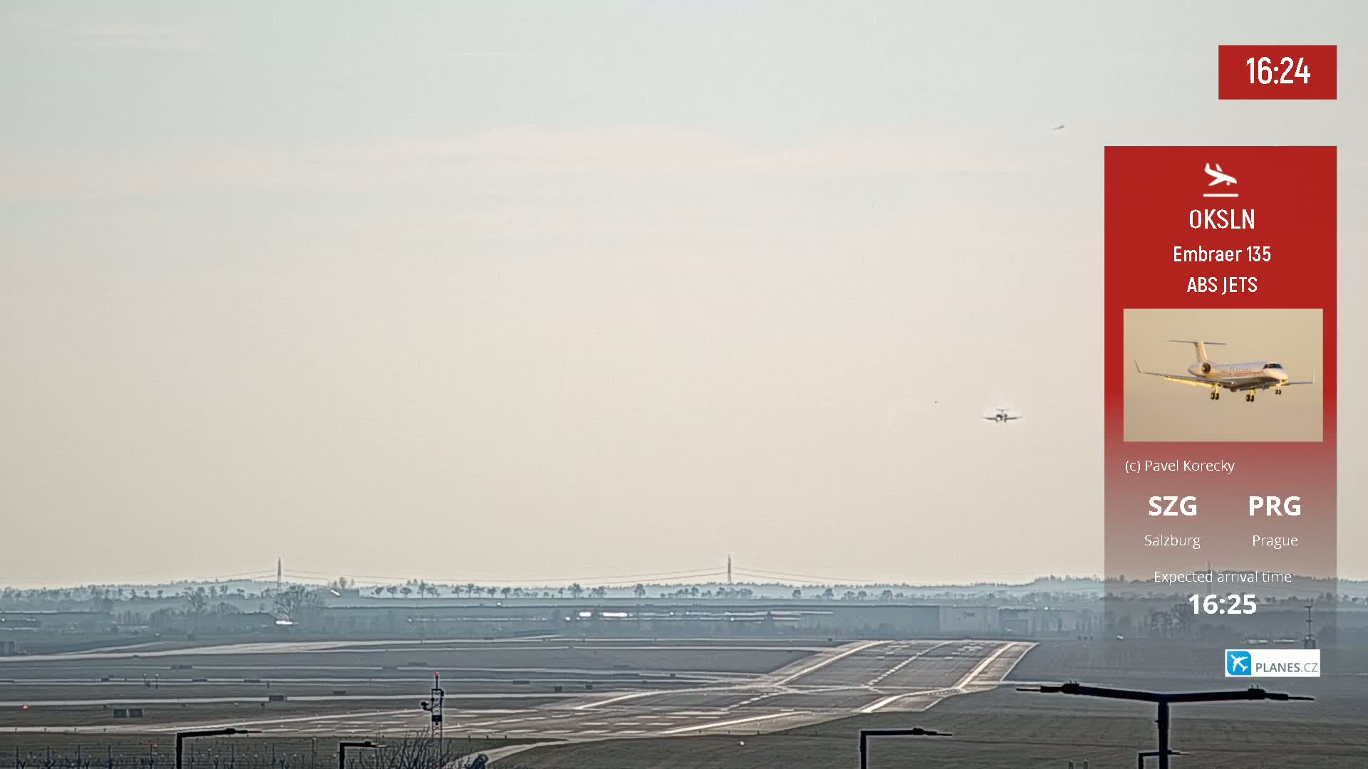 A long shot of an airport runway on a hazy day, with a small airplane in the distance.