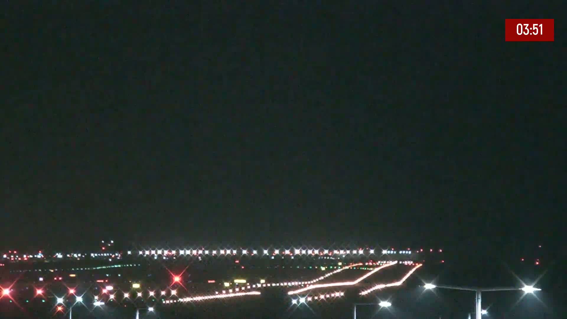 A nighttime view of a runway illuminated with lights under a dark sky.