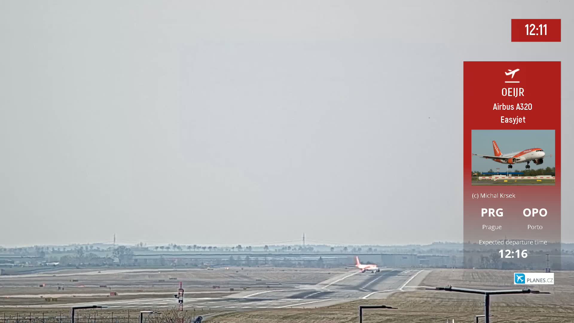 An orange and white airplane taxis on a runway under hazy conditions.