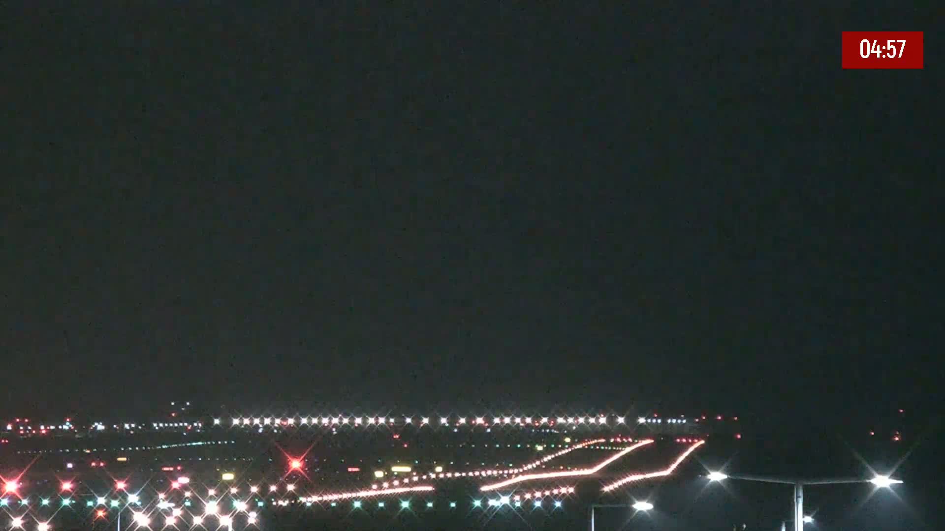 A nighttime view of an airport runway illuminated by numerous lights under a dark sky.