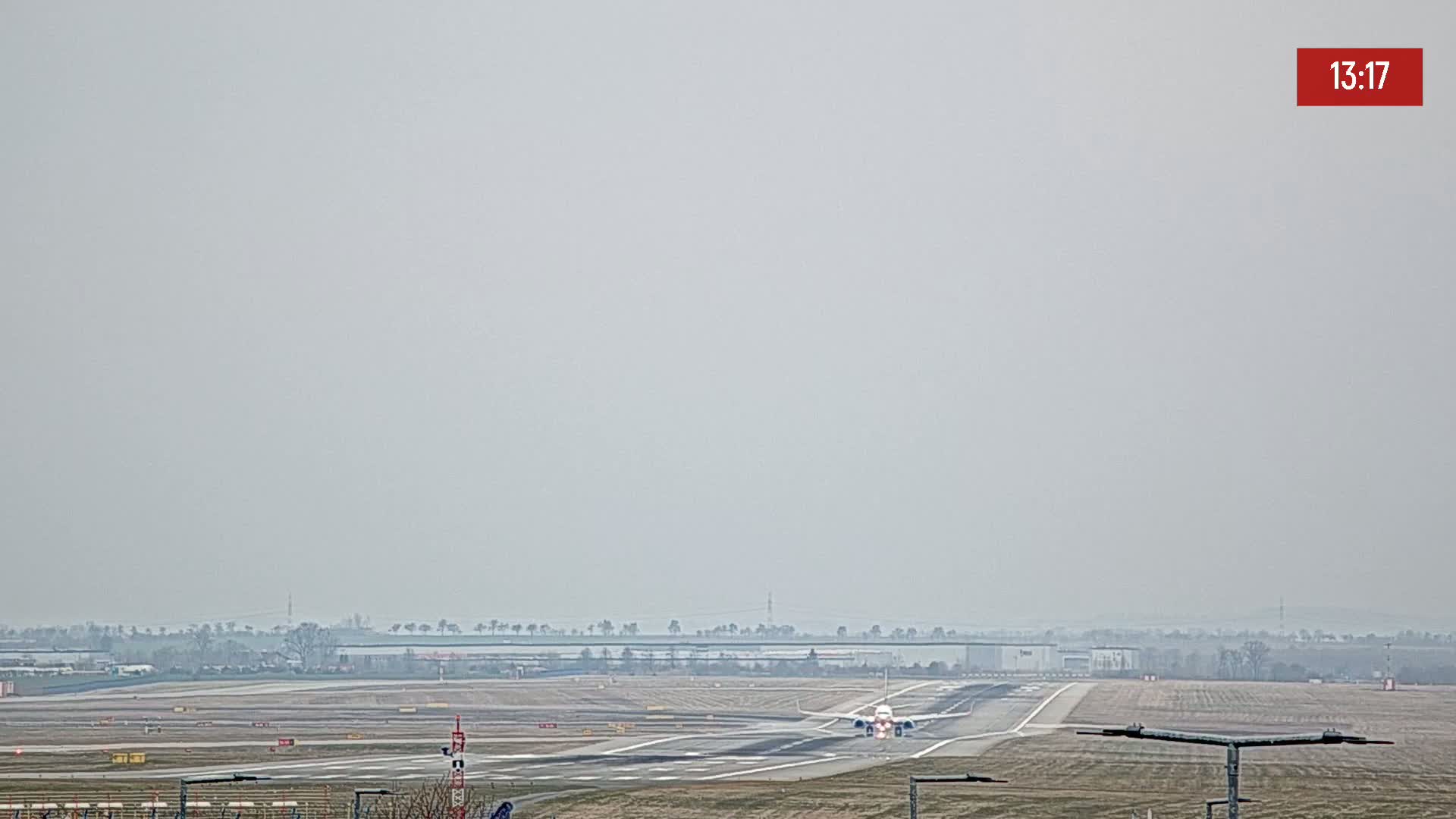 A commercial airplane is landing on a runway on an overcast day.