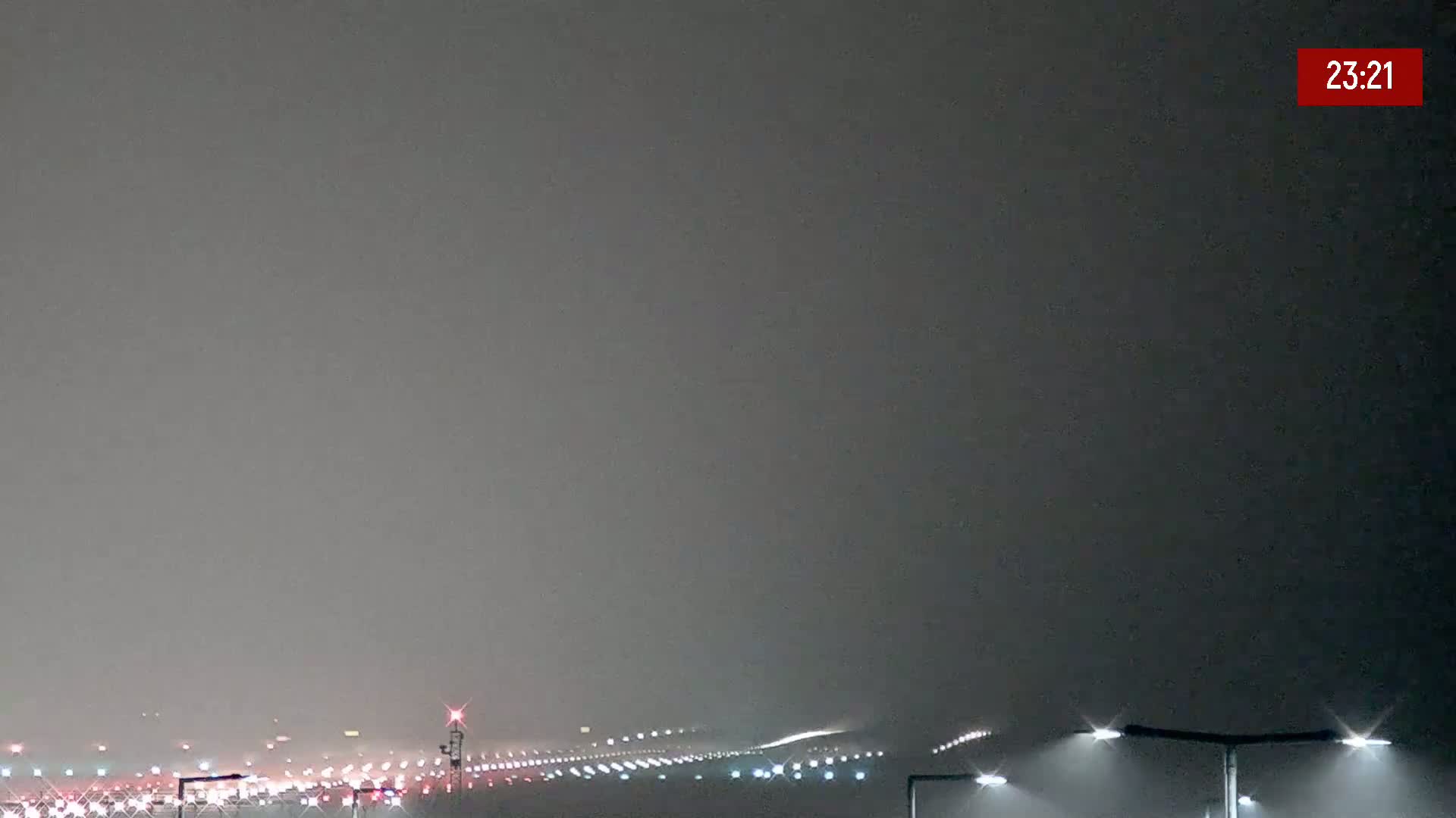 A foggy night scene shows a highway with distant lights and a runway with illuminated lights.