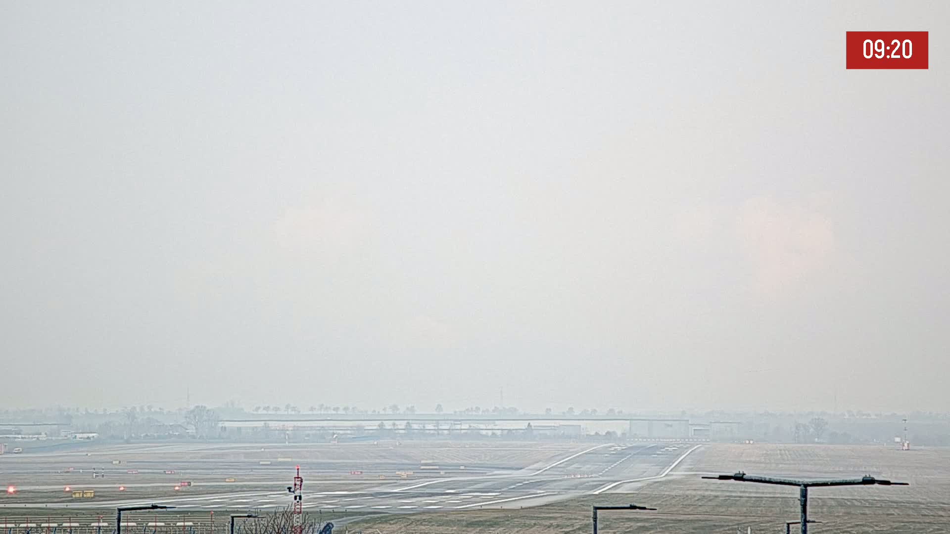 A hazy view of an airport runway and taxiways on a foggy day.