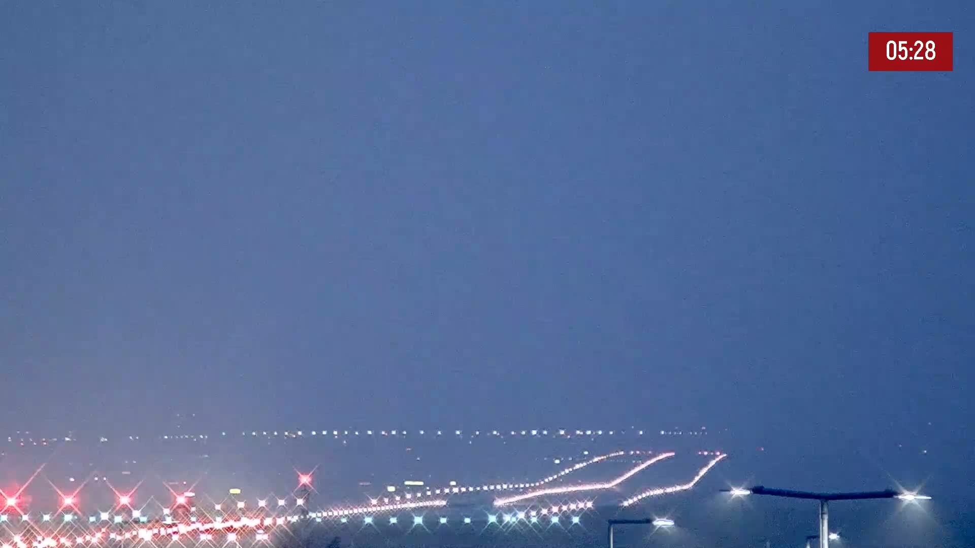 Under a twilight sky, a multi-lane highway stretches into the distance, illuminated by the headlights of numerous vehicles.