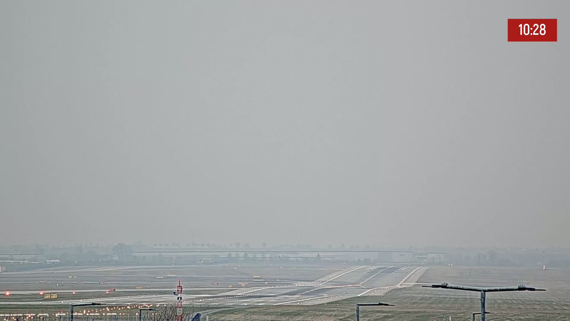 A hazy view of an airport runway and surrounding flat land.