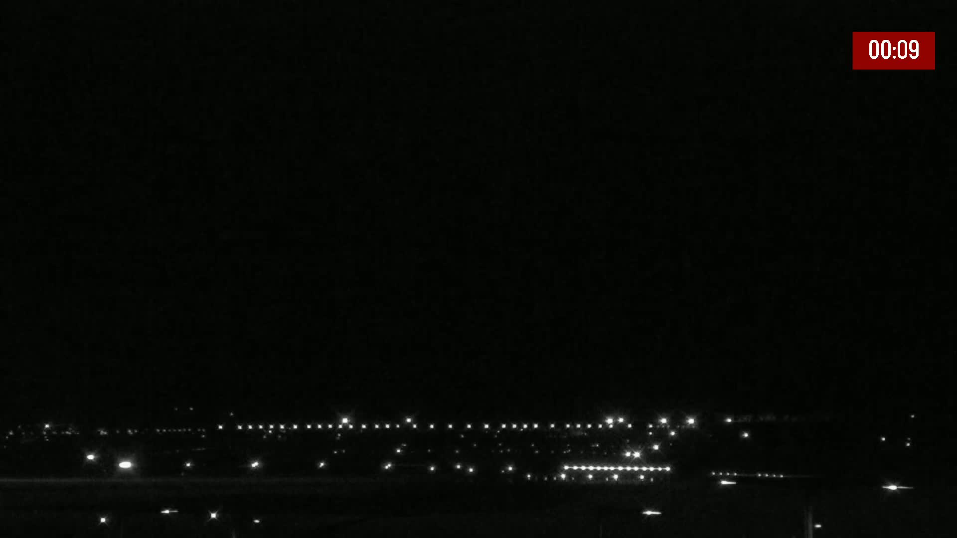 A nighttime, dark, and clear view shows a distant line of lights on the horizon.