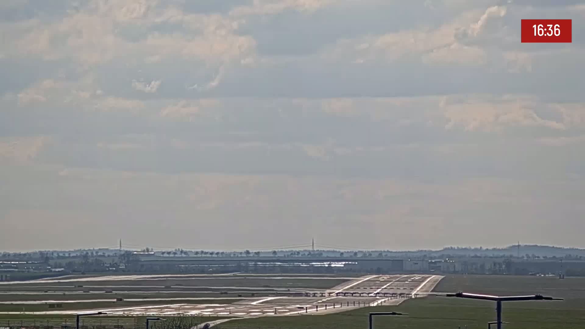A long runway extends to the horizon under a partly cloudy sky.