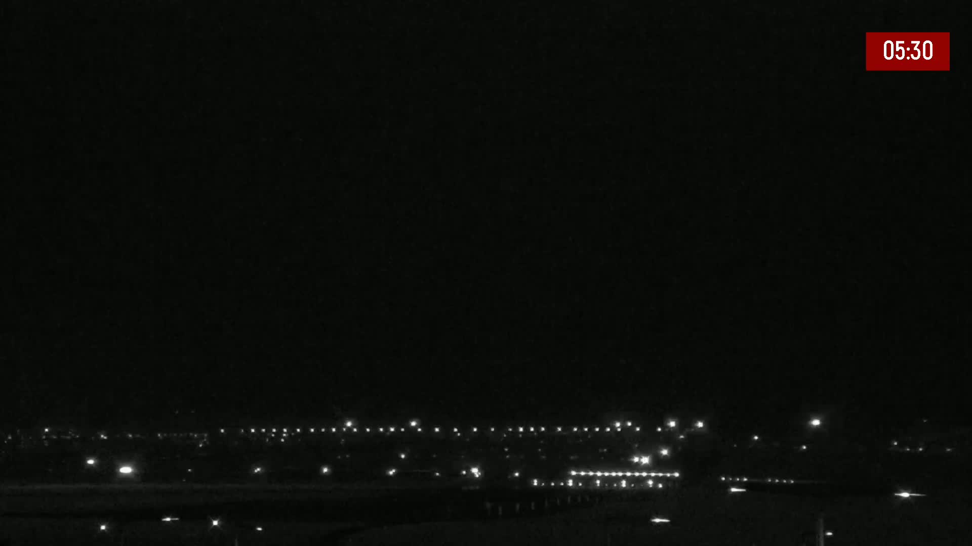 A nighttime, low-light view of a distant cityscape with scattered lights under a clear, dark sky.