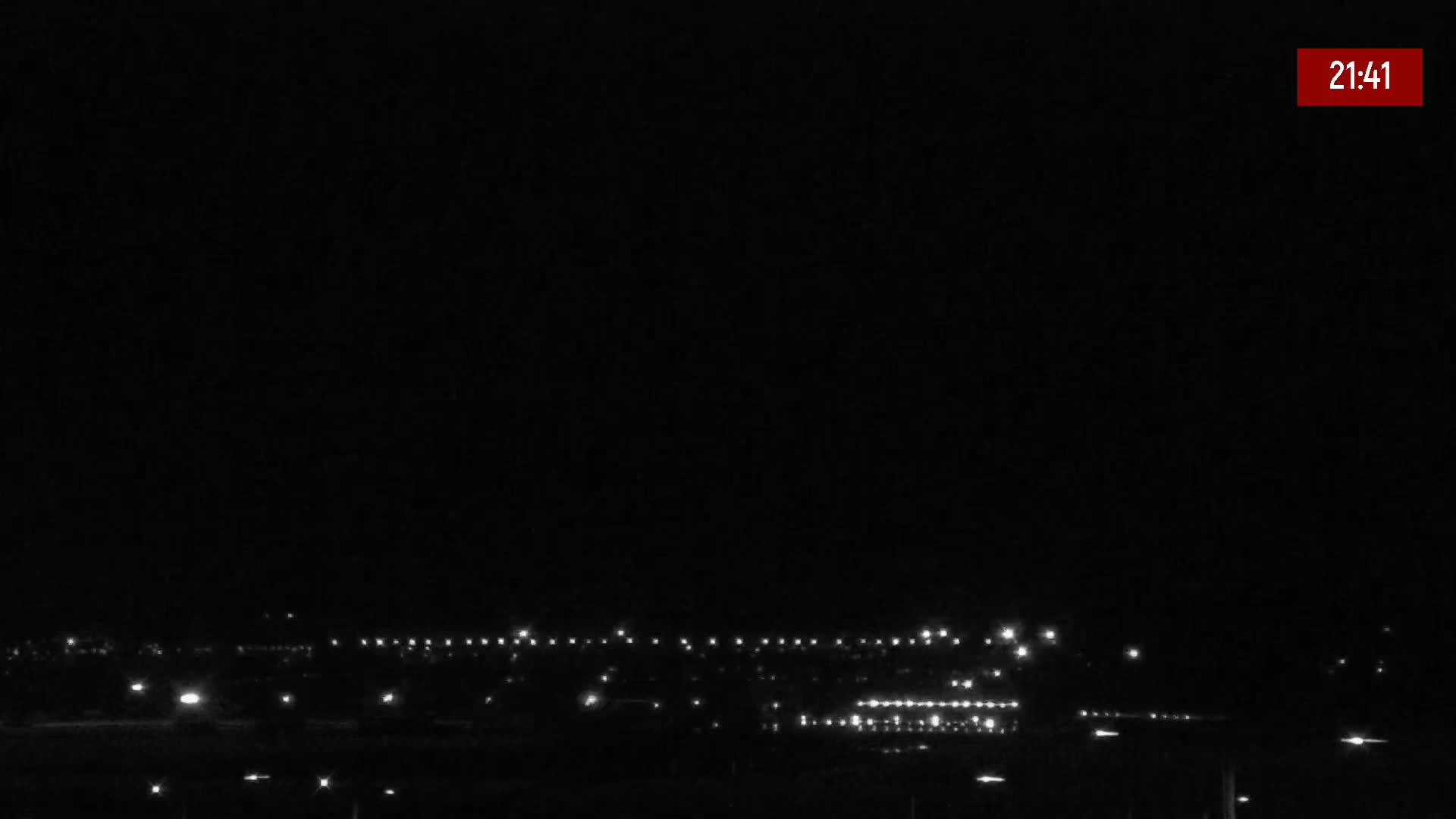 A nighttime long shot shows a line of distant lights on a dark, clear night.