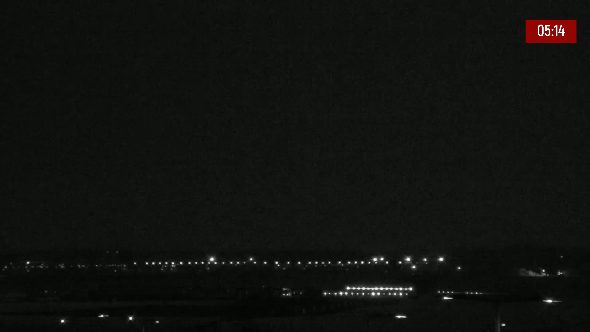 A nighttime, low-light view shows a distant line of lights on the horizon.