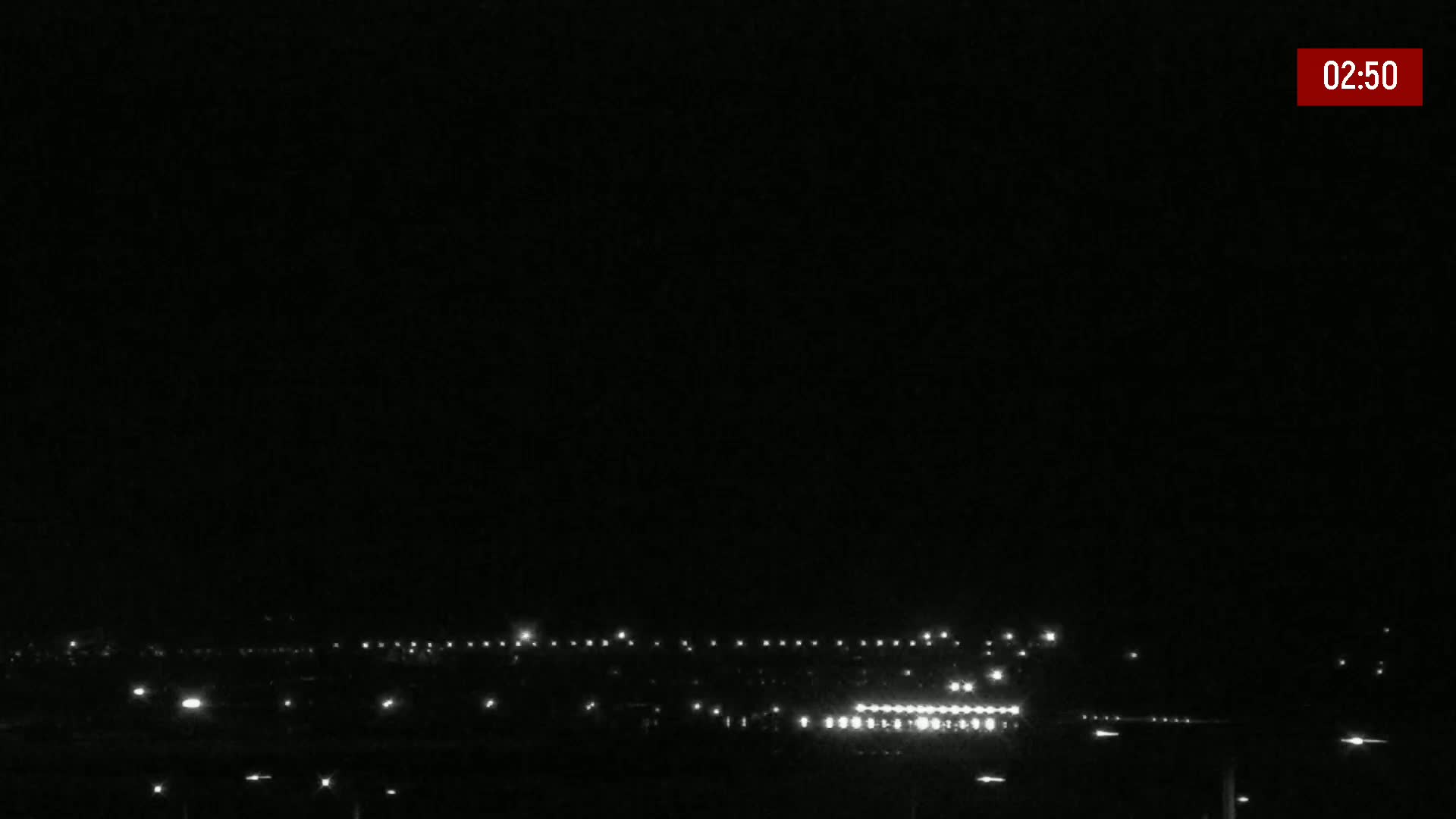 A nighttime, low-light view shows a distant line of lights, possibly a town or city, under a clear, dark sky.