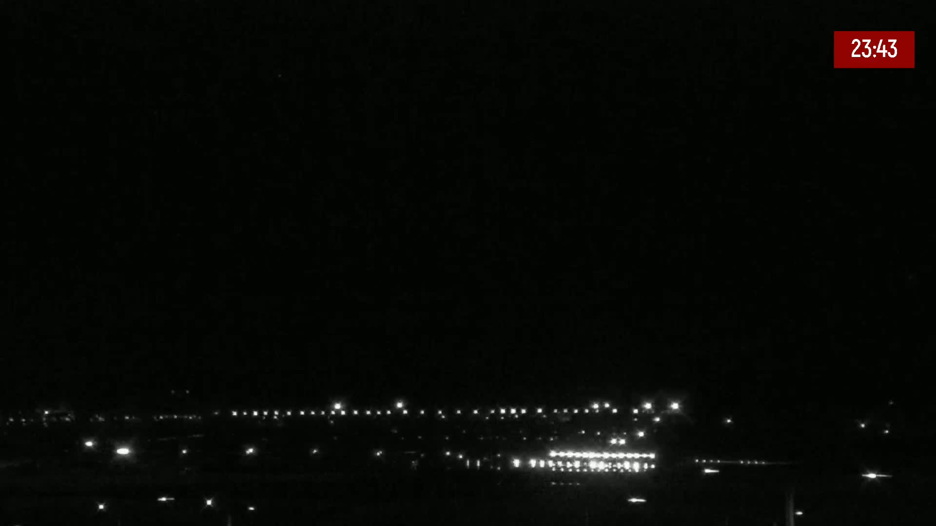 A nighttime, low-light view of a distant line of lights, likely a town or city, under a clear, dark sky.