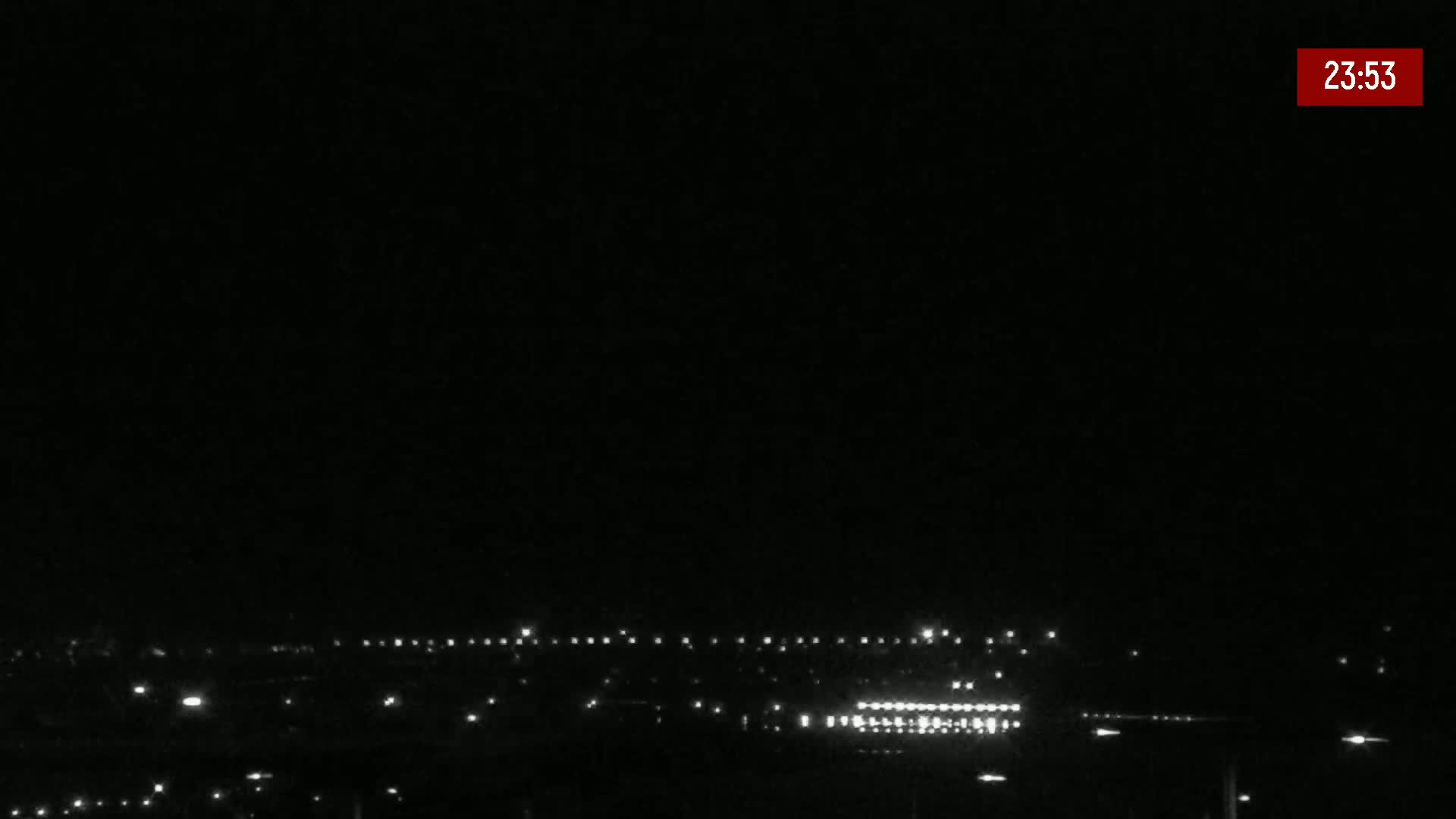 A nighttime long shot shows a distant line of city lights under a clear, dark sky.