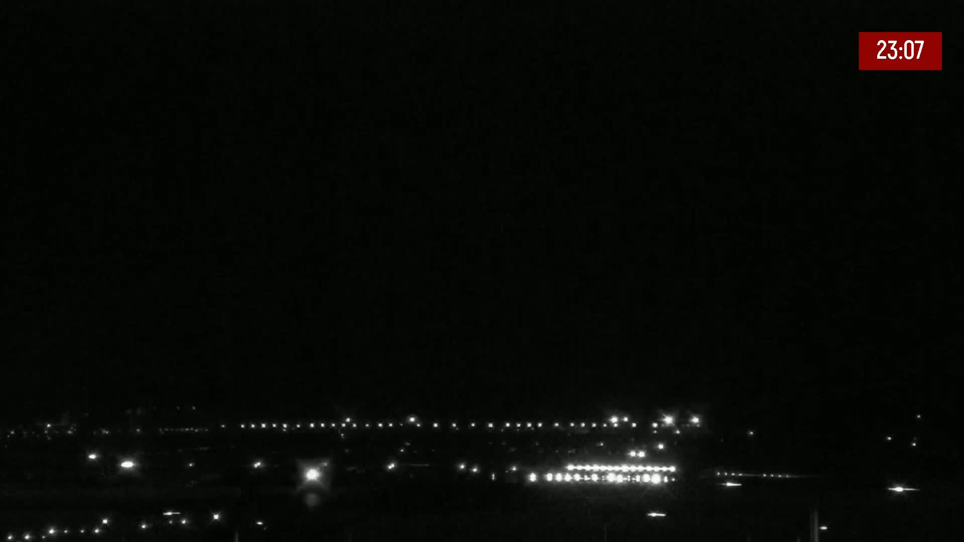 A nighttime, long shot of a distant line of lights, possibly a roadway or town, under a clear, dark sky.