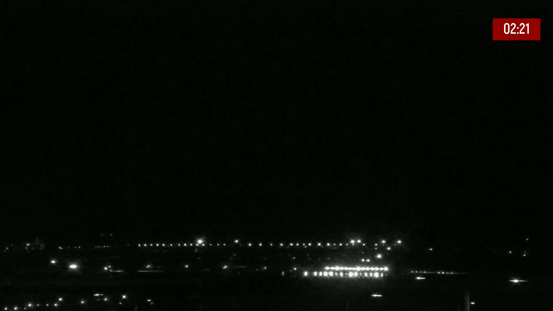 A distant line of lights from a town or city is visible at night under a dark, clear sky.
