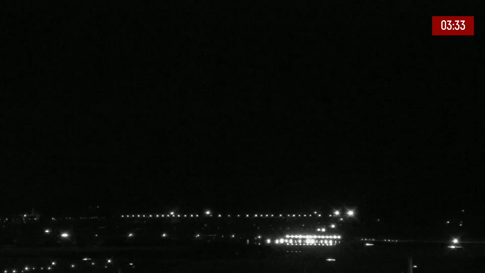 A nighttime long shot shows a distant line of lights under a dark, clear sky.