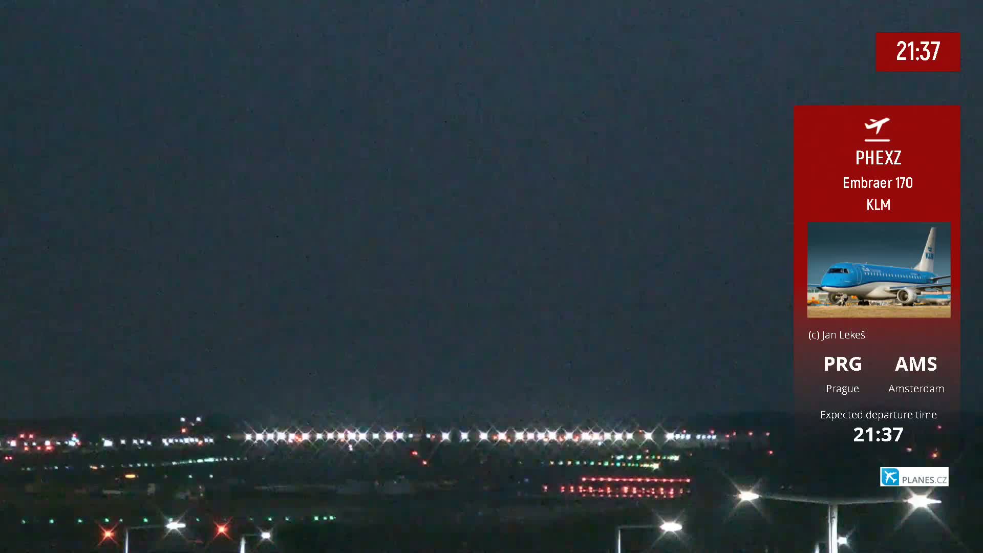 A nighttime view of an airport runway with lights illuminating the tarmac under a dark sky.