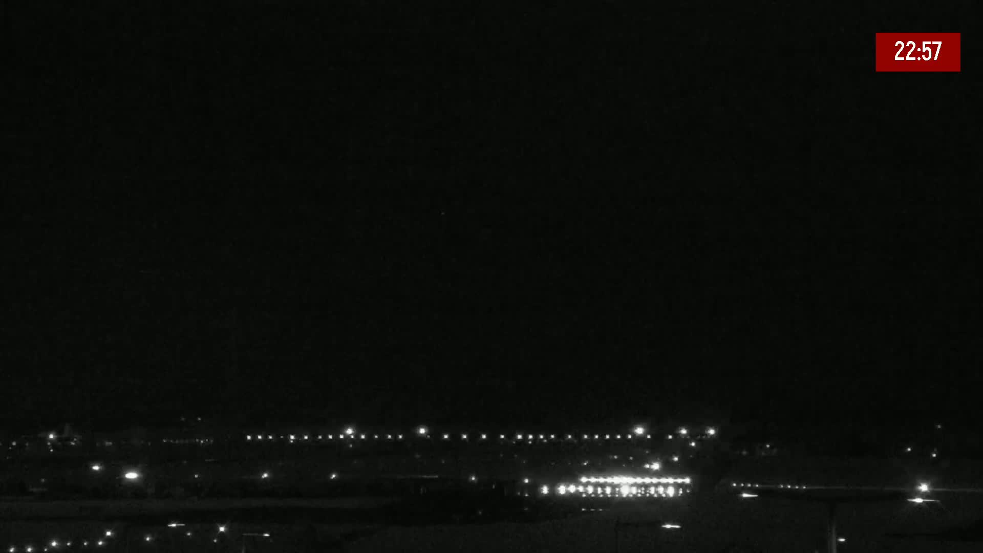 A nighttime, low-light view of a long line of lights, possibly from a highway or airport runway, under a clear, dark sky.