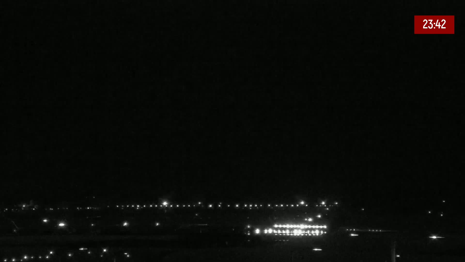 A nighttime, low-light view of a runway with numerous lights illuminating the ground.