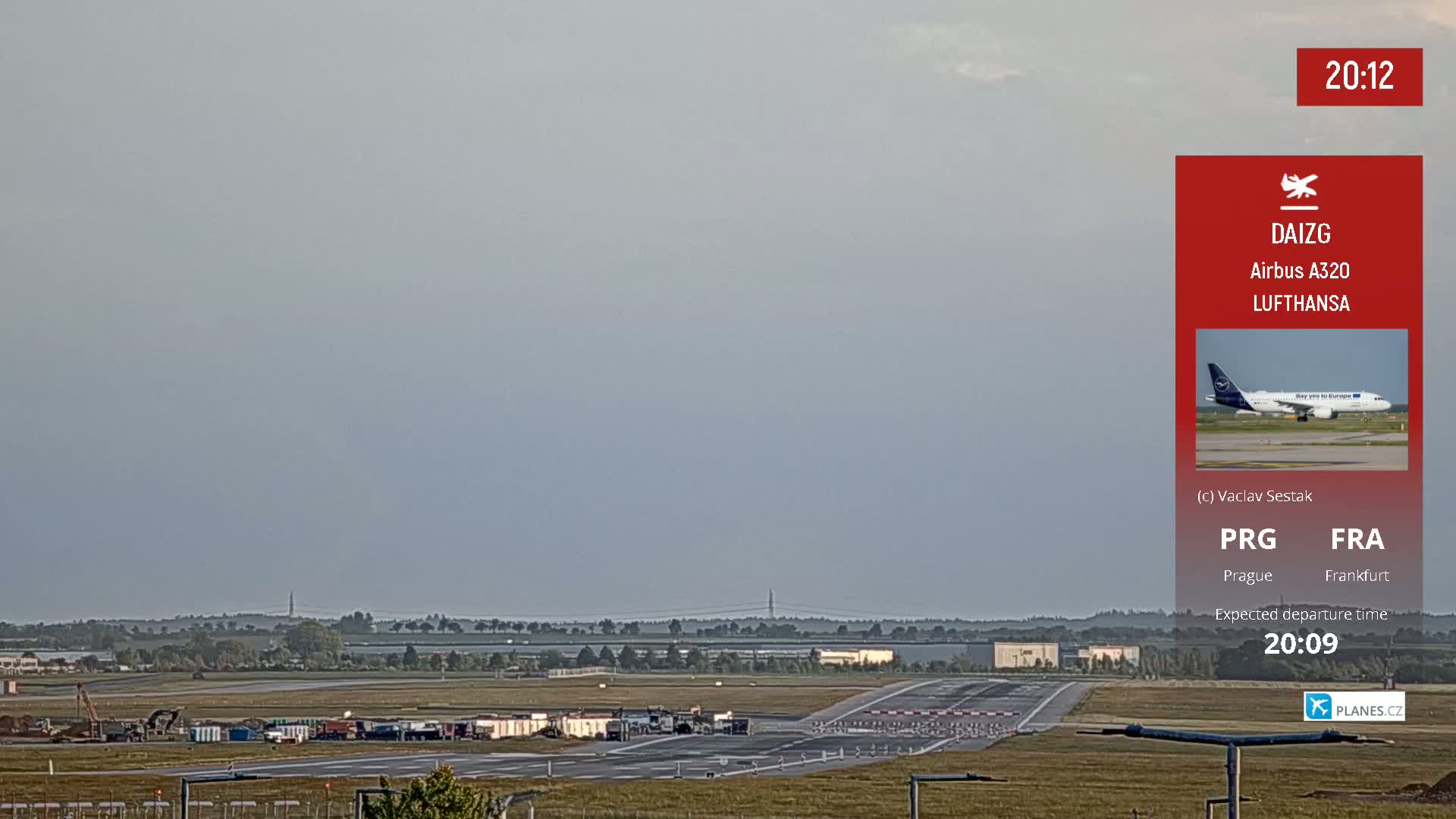 An airport runway is visible under a hazy sky, with construction equipment and vehicles present near the tarmac.
