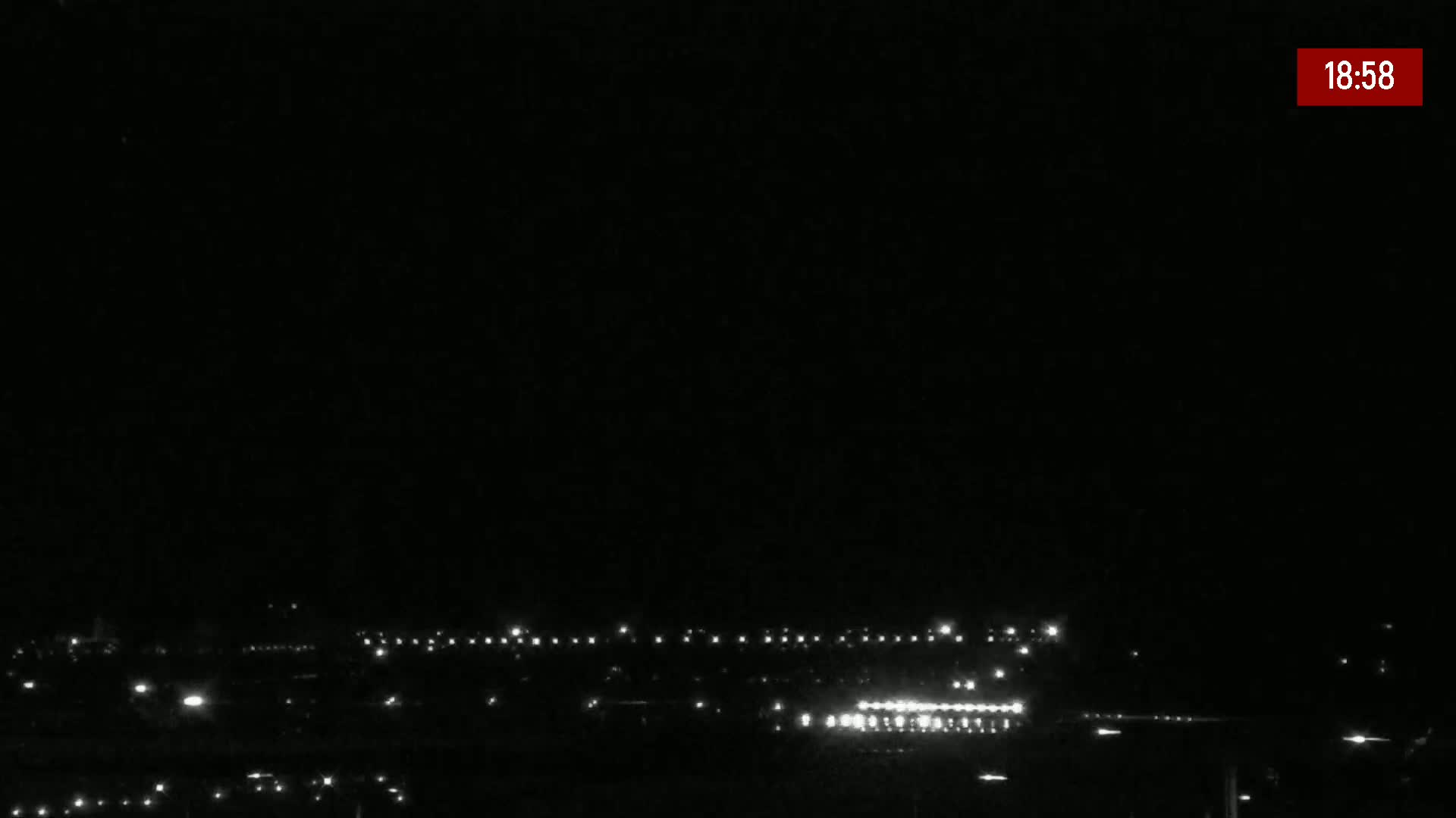 A nighttime, long shot shows a line of lights in the distance under a dark, clear sky.