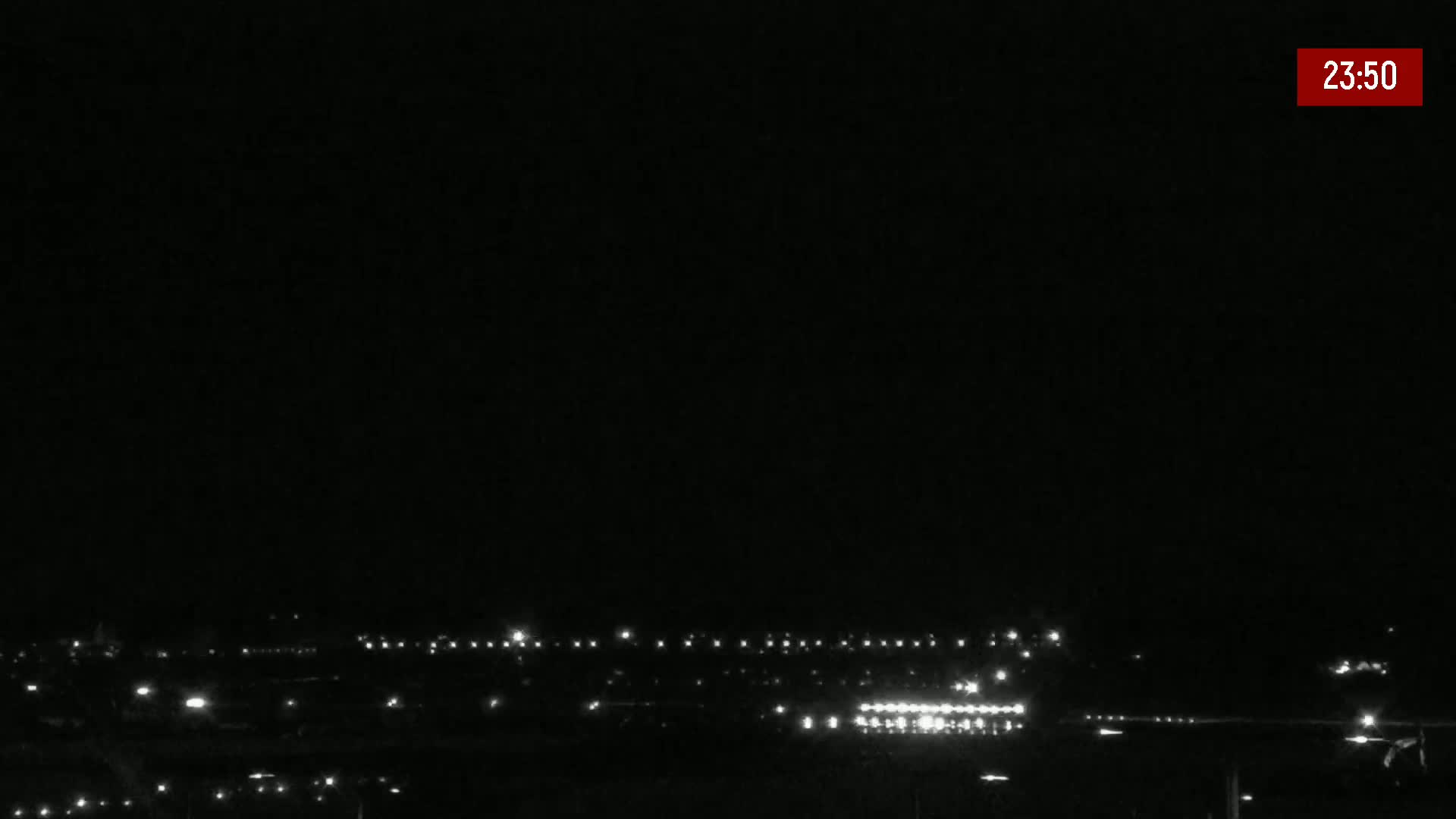A nighttime, long shot of a distant line of lights, possibly a town or city, under a clear, dark sky.
