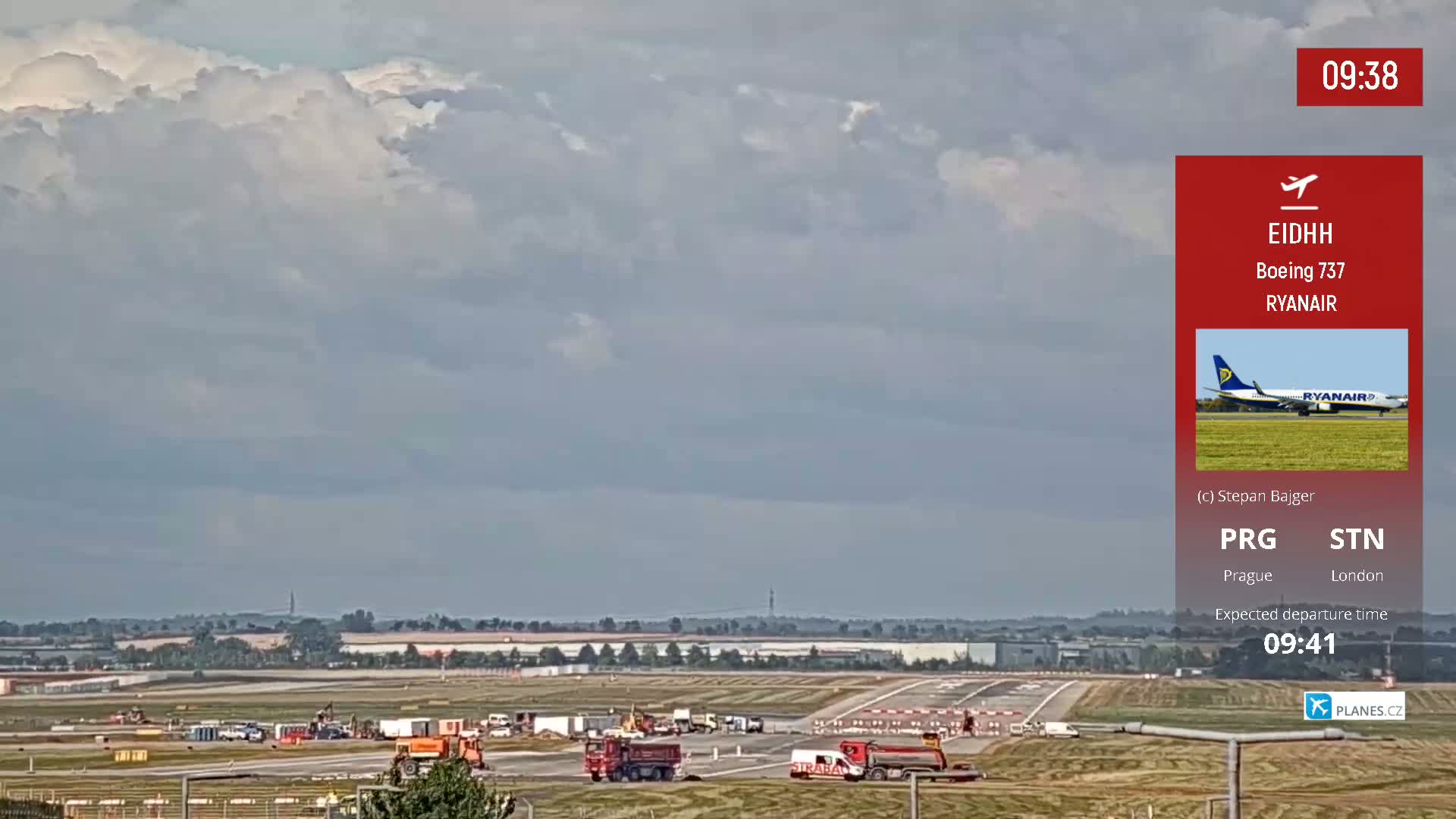 A mostly cloudy sky hangs over an airport runway where construction equipment is visible and a Ryanair Boeing 737 is preparing for departure.