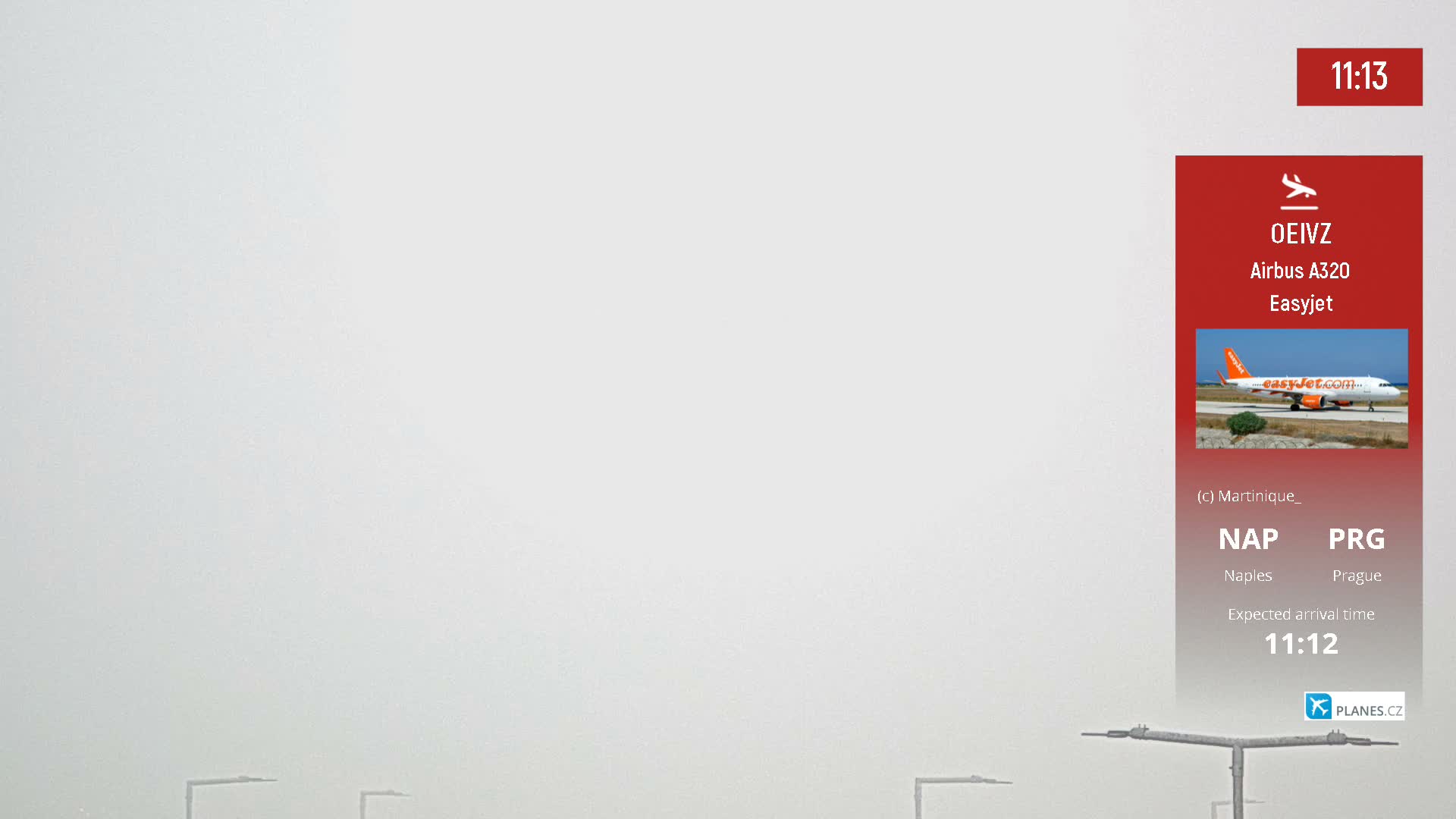 The image shows a large, plain light grey background, partially overlaid on the right by a red-orange panel featuring a vibrant photograph of an orange and white airplane on a sunny tarmac under a clear blue sky, with faint dark structural elements visible near the bottom edge.