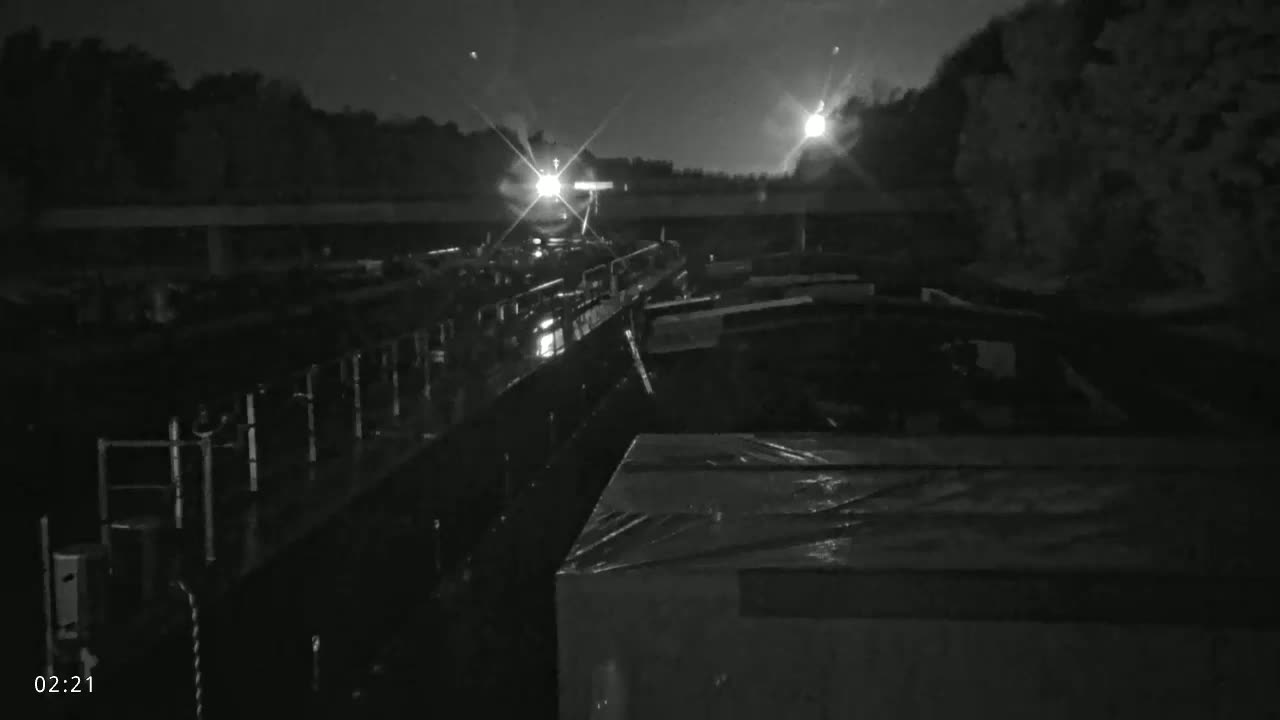 A nighttime view of several barges docked along a waterway under a dark, possibly overcast sky.