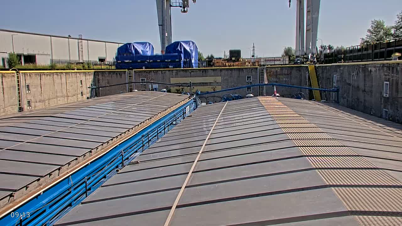 The image shows the gray metal roof of a vessel in a lock, under a sunny sky.