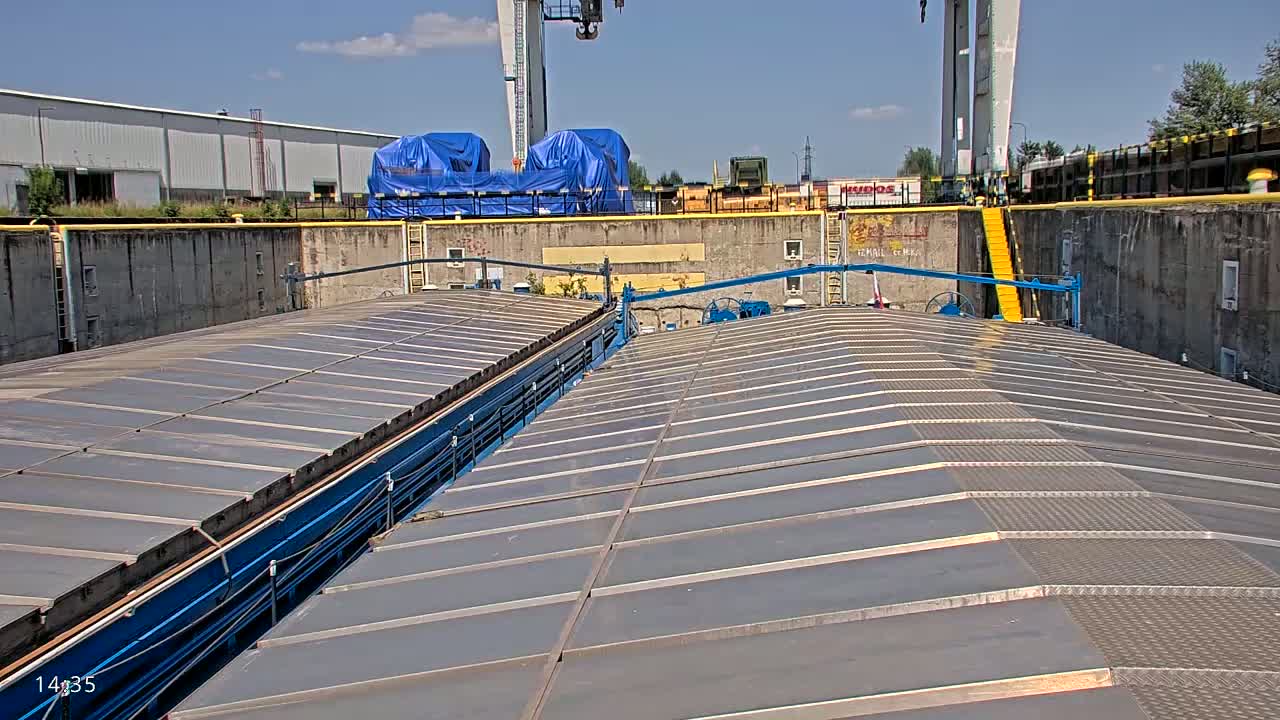 A view from the top of a barge in a lock, under sunny skies.