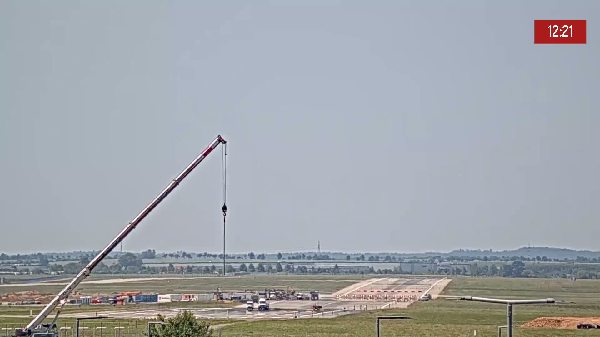 A large crane is positioned on an airfield under a hazy sky.