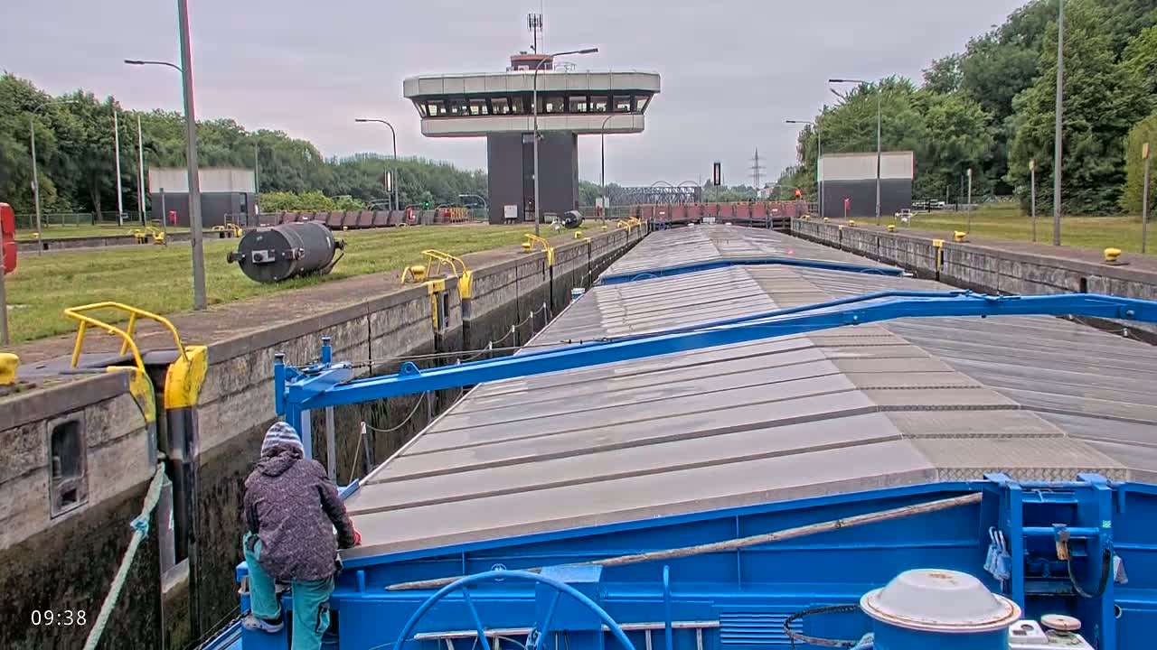 A blue barge is traveling through a lock on an overcast day.
