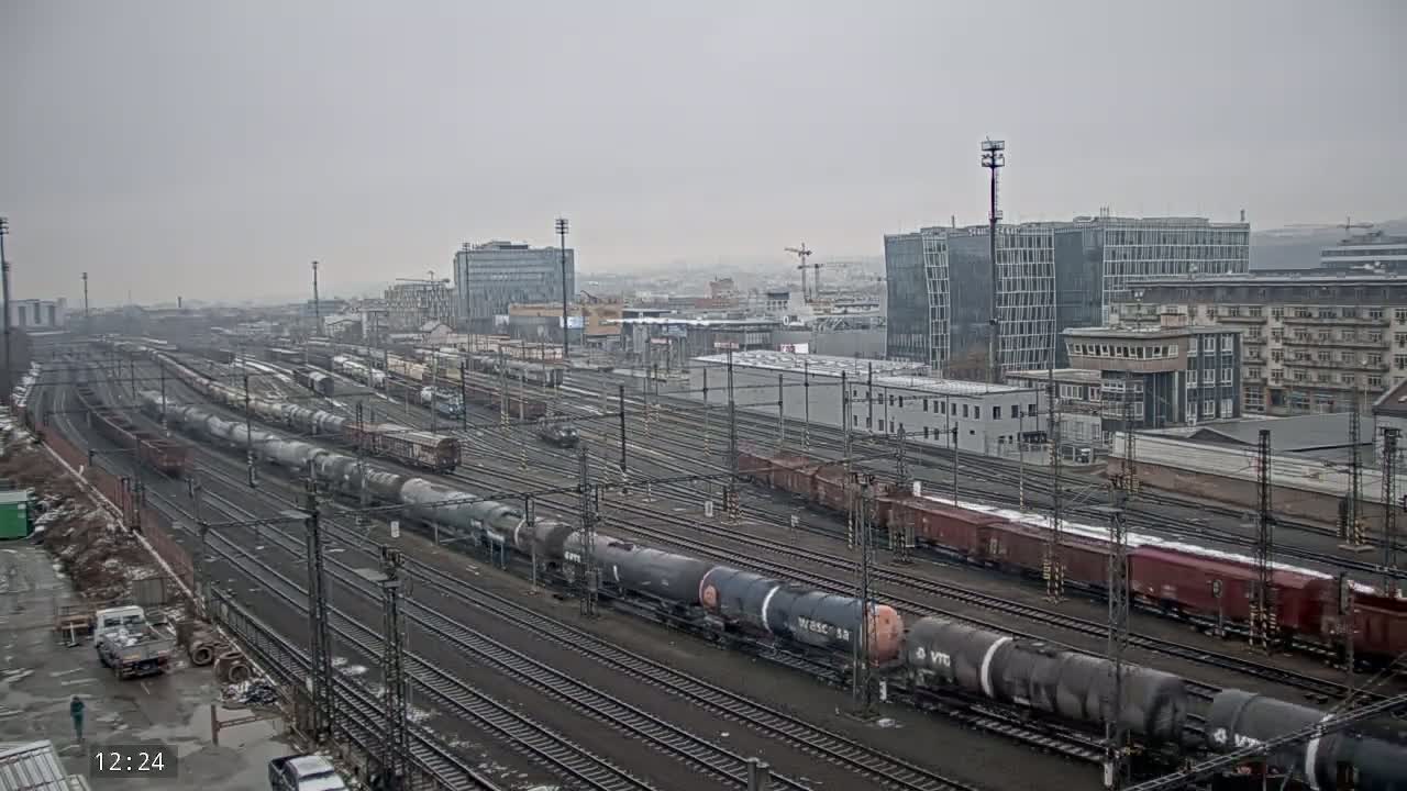 A wide shot of a railway yard with numerous freight trains under an overcast sky.